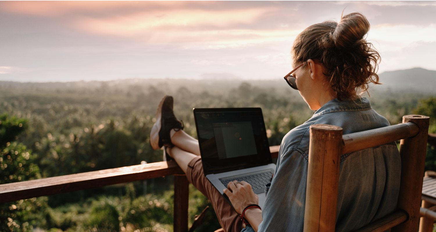 Woman on laptop with feet up on balcony