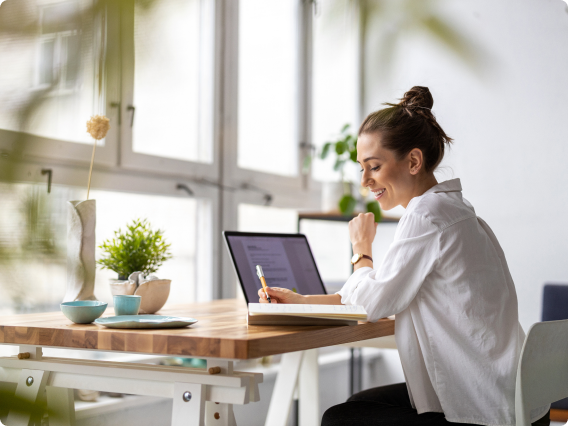 Person writing while using a laptop